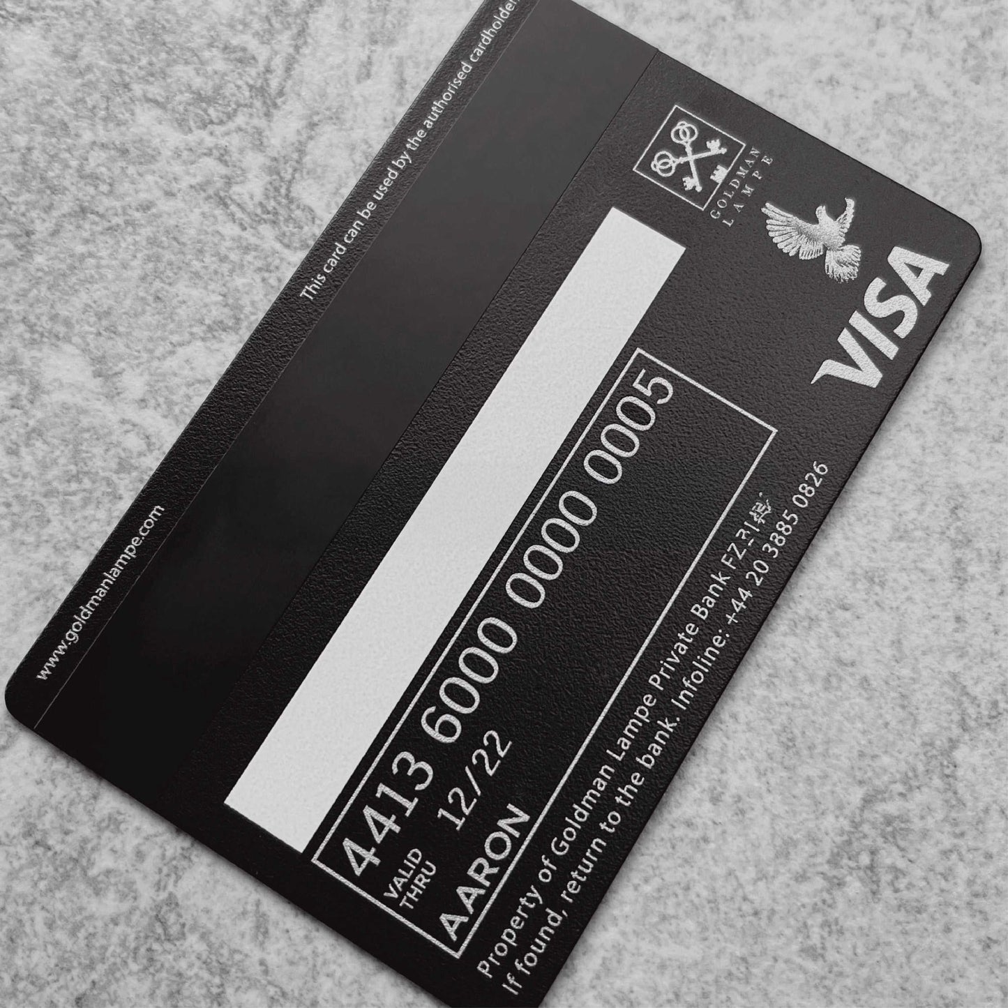 Black metal Visa card with silver details on a textured surface, luxury credit card design
