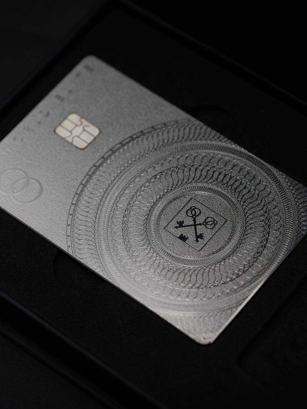 Silver metal card with intricate engraved pattern and keys emblem in black presentation box