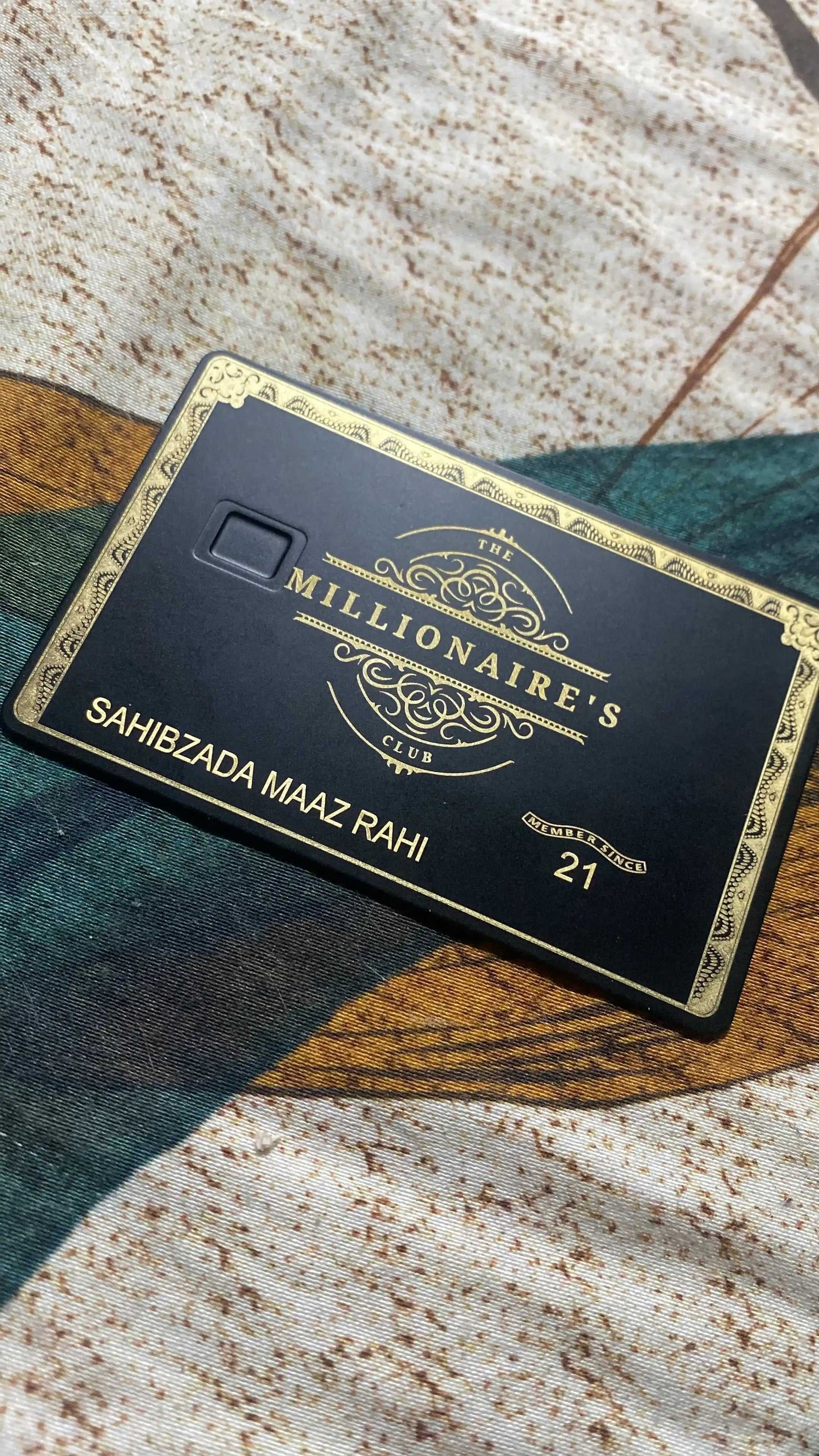 Black and gold metal card with 'The Millionaire's Club' and embossed details on fabric.