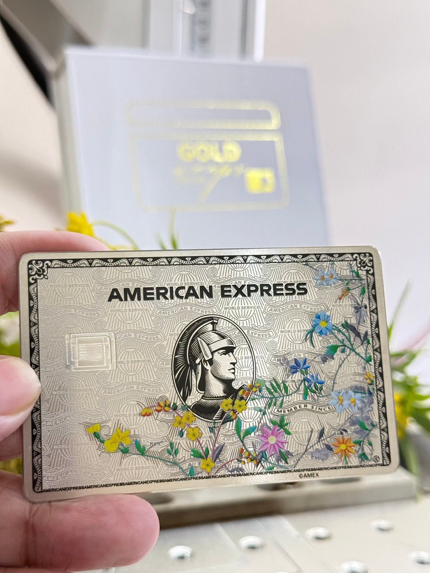 Custom metal American Express card with floral design held in hand, luxury credit card product