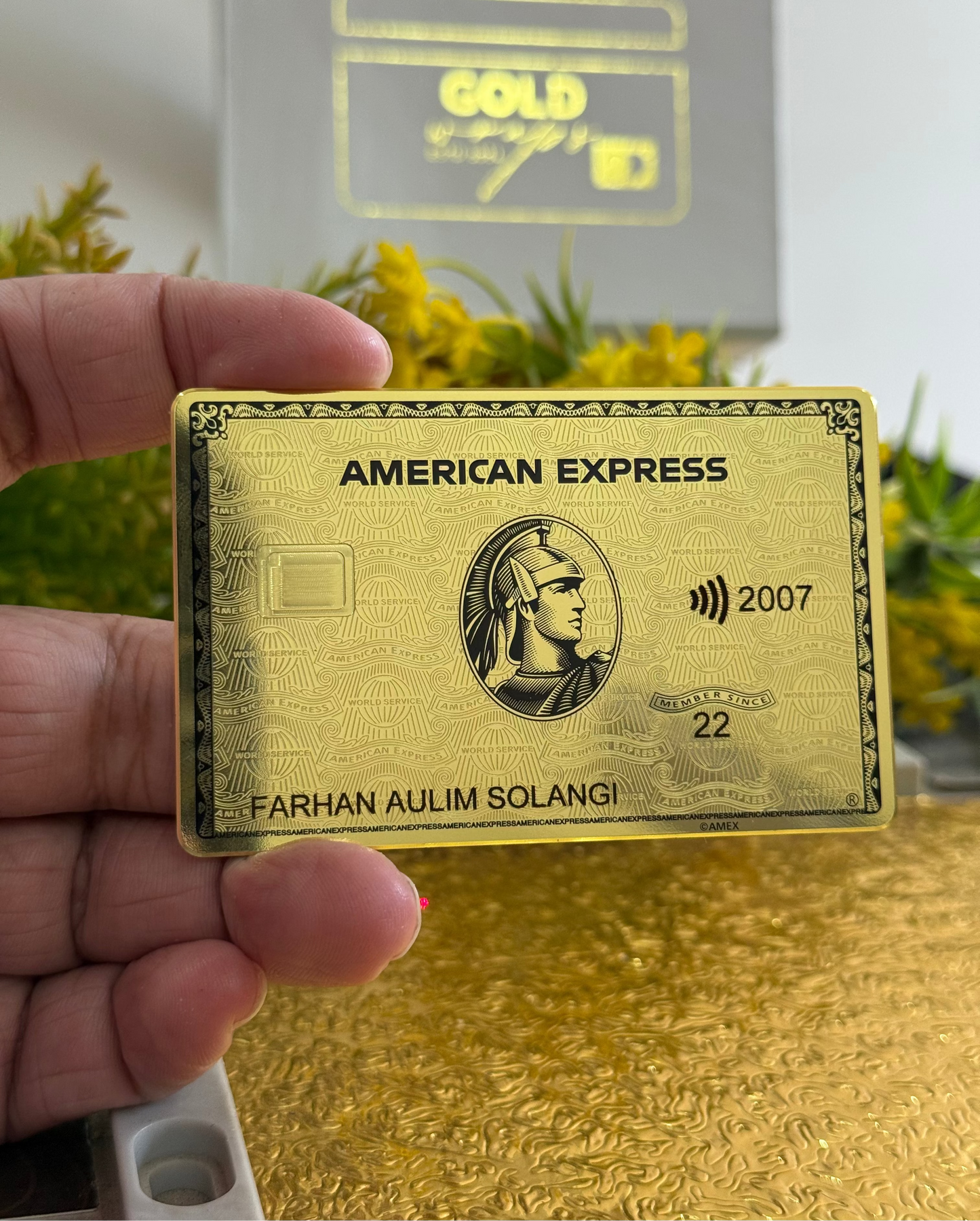Gold American Express card held by a hand with a blurred background