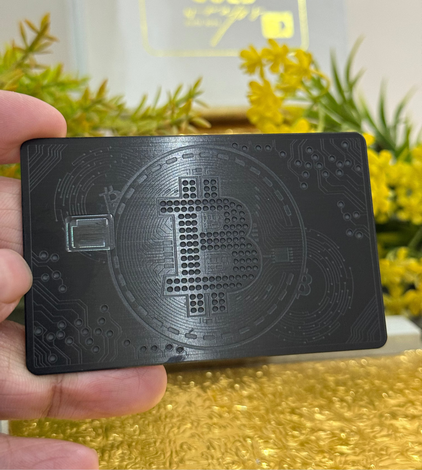 Black card with Bitcoin symbol held by a hand against a blurred natural background