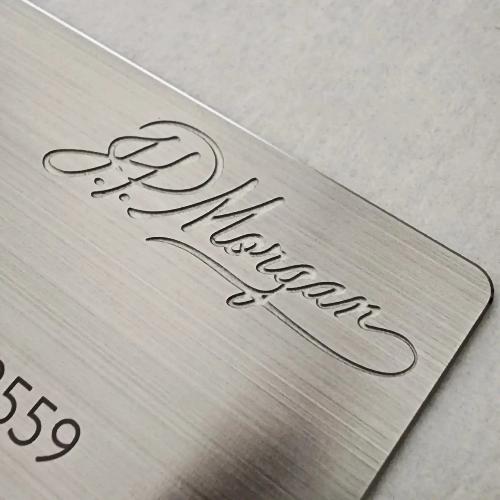 Brushed silver metal card with engraved script and rounded corner on light background