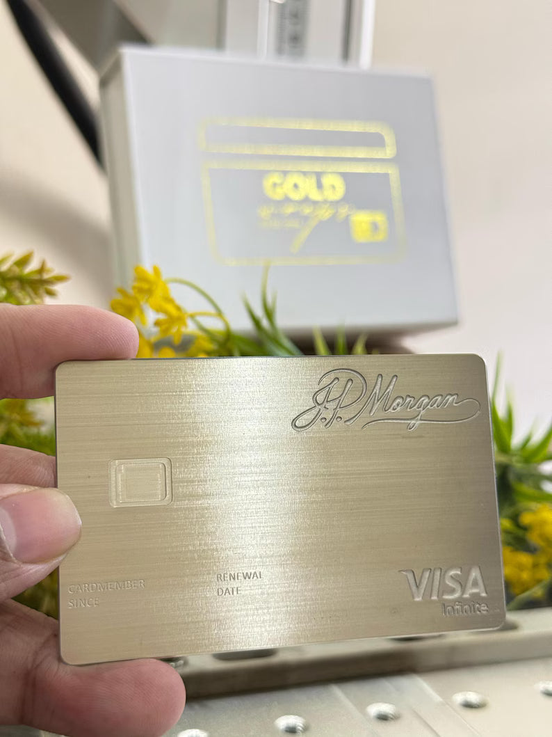 J.P. Morgan metal credit card with brushed gold finish and Visa Infinite logo, held by hand