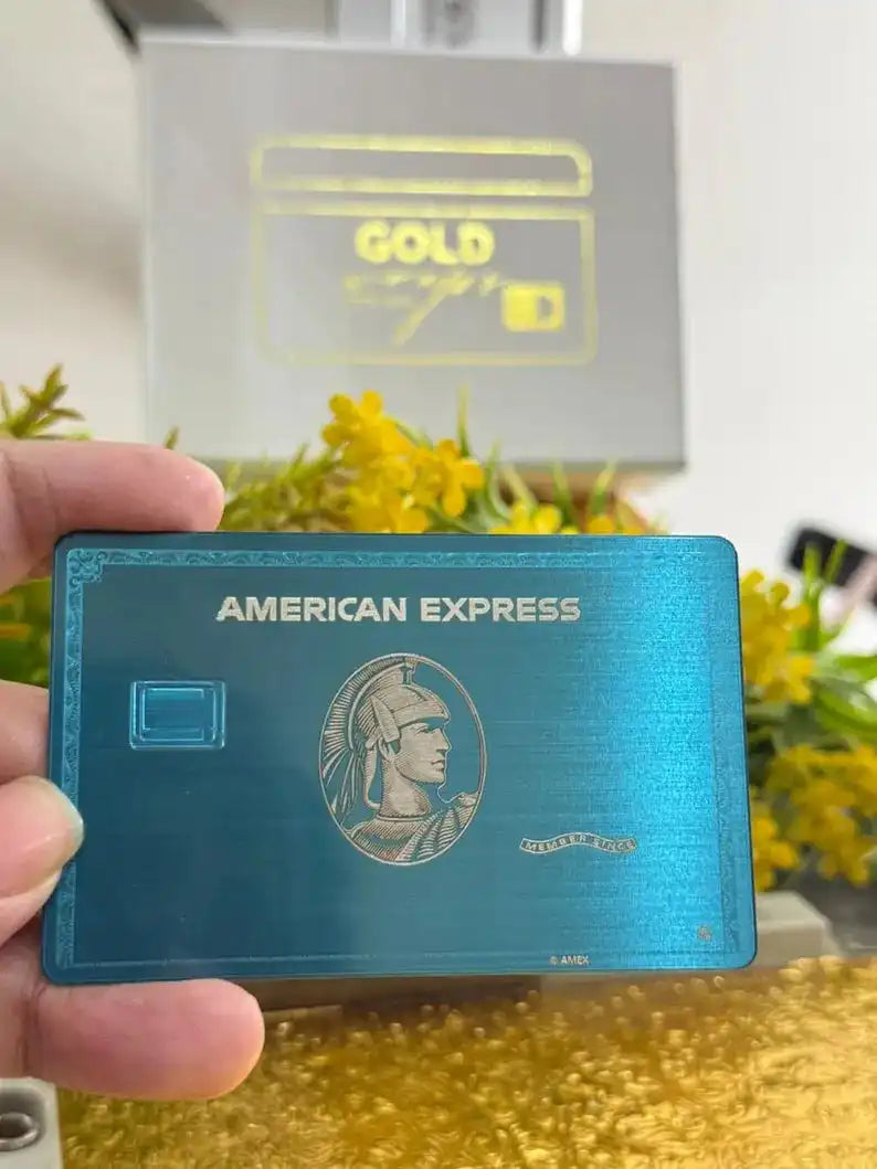 Hand holding blue metal American Express card with gold flowers and gift box in background