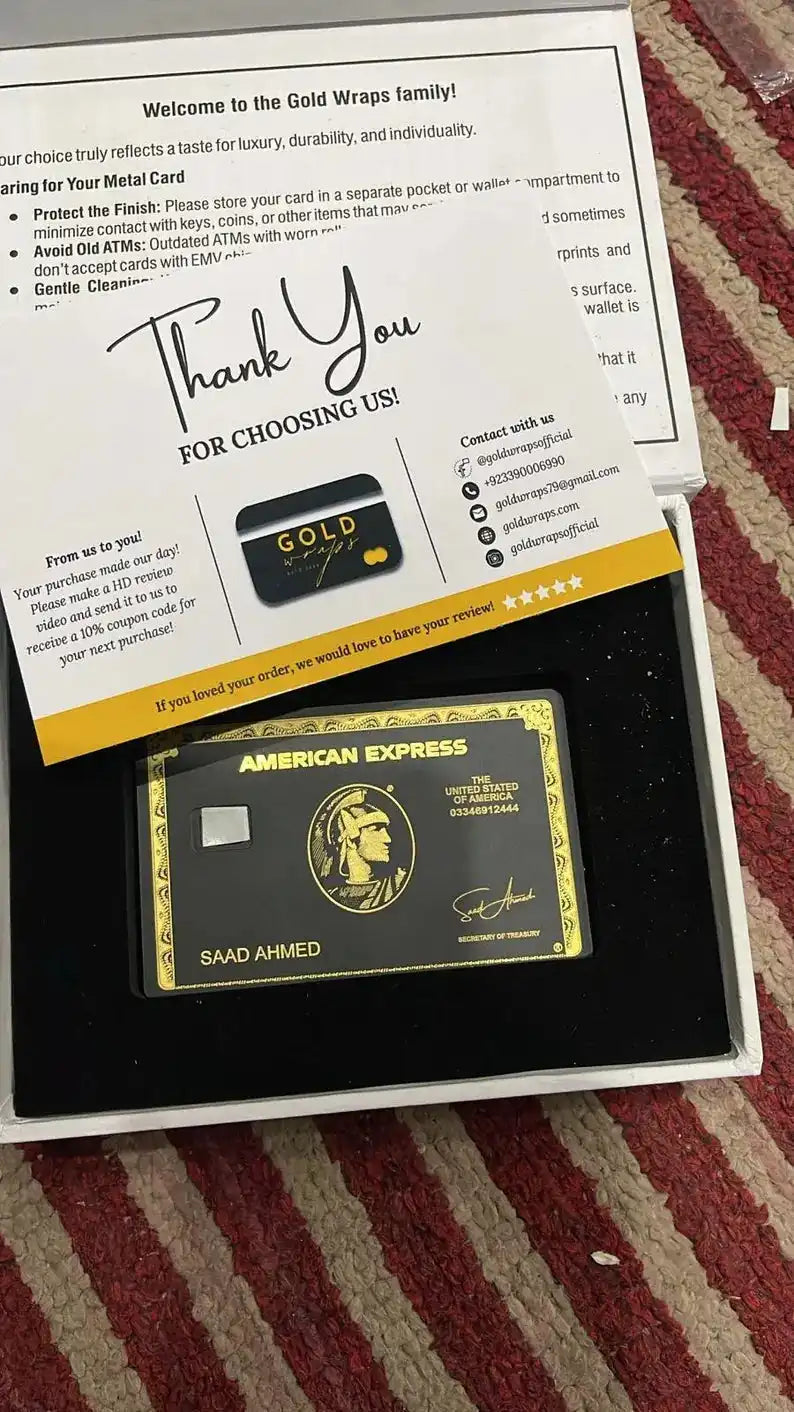 Luxury black and gold metal American Express card in gift box with thank you note on striped rug