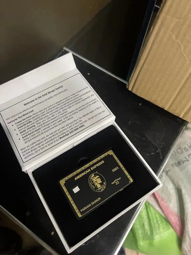 Black and gold metal American Express card in gift box with care instructions insert